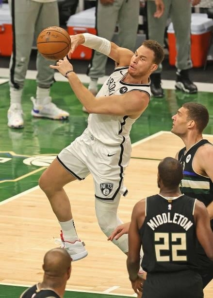 Blake Griffin of the Brooklyn Nets passes over Brook Lopez and Khris Middleton of the Milwaukee Bucks at Fiserv Forum on June 17, 2021 in Milwaukee,...