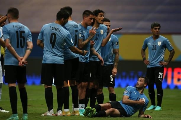 Luis Suarez of Uruguay gives instructions to teammate Matias Viña as they prepare for a free kick of Argentina during a group A match between...