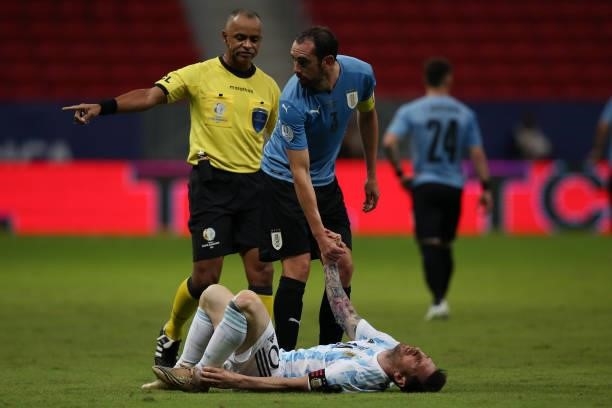 Diego Godin of Uruguay helps Lionel Messi of Argentina after suffering an injury during a group A match between Argentina and Chile as part of...