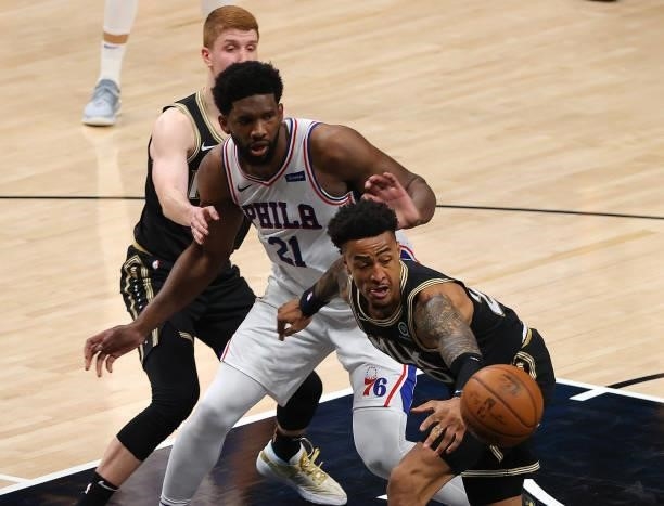John Collins of the Atlanta Hawks reaches for a loose ball against Joel Embiid of the Philadelphia 76ers during the first half of game 6 of the...
