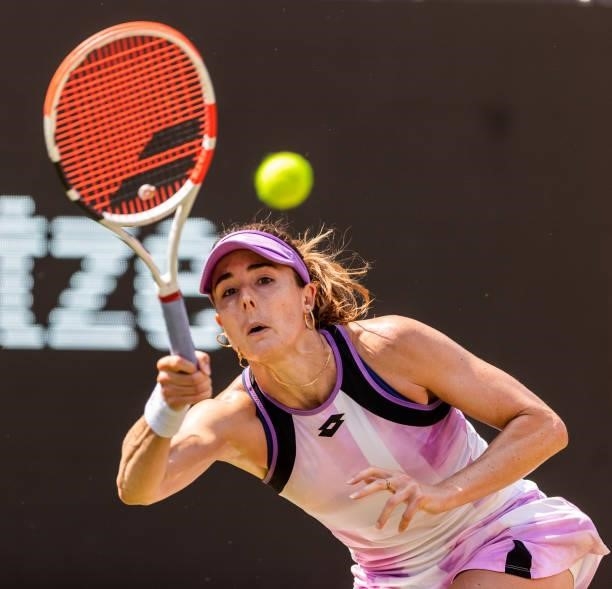 Alize Cornet of France stretches to play a forehand against Belinda Bencic of Switzerland in the women's singles semifinal match during day 8 of the...