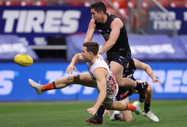 Toby Greene of the Giants kicks whilst being tackled by Jacob Weitering of the Blues during the round 14 AFL match between the Greater Western Sydney...