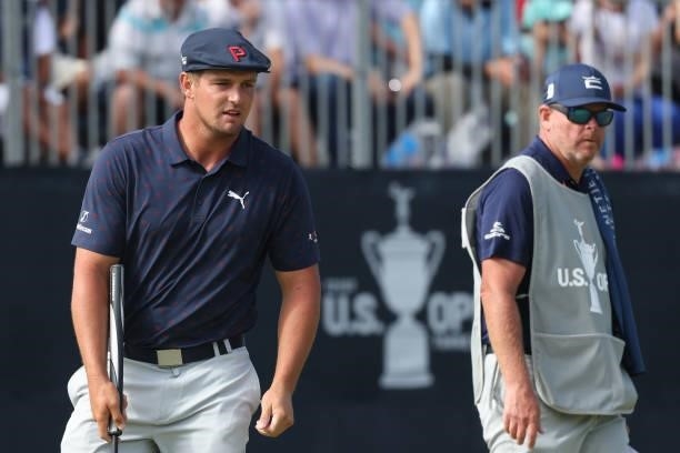 Bryson DeChambeau of the United States reacts to his putt on the 18th green as caddie Tim Tucker looks on during the third round of the 2021 U.S....