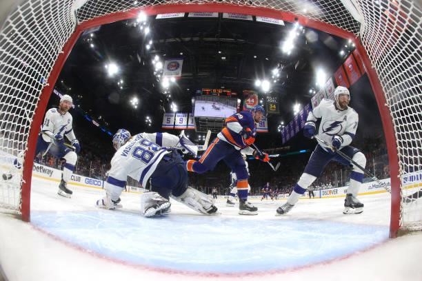 Brock Nelson of the New York Islanders and Mathieu Joseph of the Tampa Bay Lightning watch the puck after Andrei Vasilevskiy blocked a shot in Game...