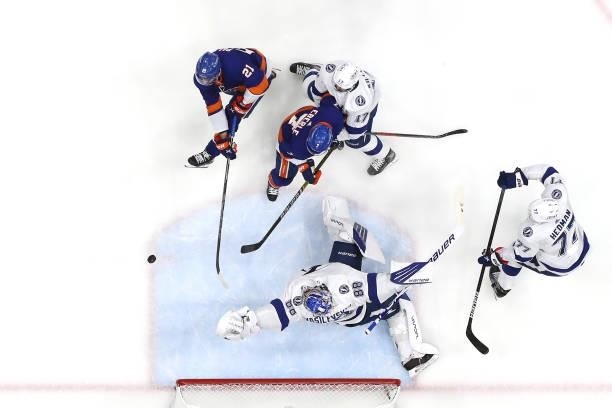 Andrei Vasilevskiy of the Tampa Bay Lightning reaches for the puck while defending against Kyle Palmieri of the New York Islanders and Jordan Eberle...
