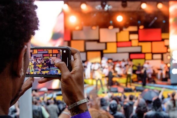 Man takes photos with his phone as Billy Davis and Marilyn McCoo perform during Questlove's "Summer Of Soul