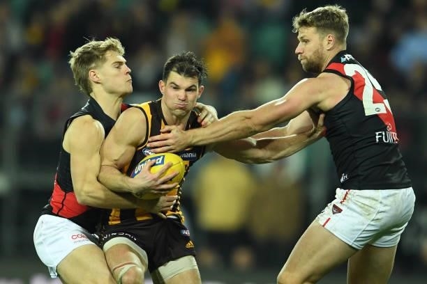 Jaeger O'Meara of the Hawks is tackled by Jake Stringer and Ned Cahill of the Bombers during the round 14 AFL match between the Hawthorn Hawks and...