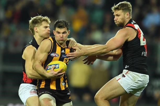 Jaeger O'Meara of the Hawks is tackled by Jake Stringer and Ned Cahill of the Bombers during the round 14 AFL match between the Hawthorn Hawks and...