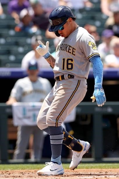 Kolten Wong of the Milwaukee Brewers gestures as he crosses home plate after hitting a 2 RBI home run against the Colorado Rockies in the second...