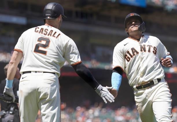 Donovan Solano of the San Francisco Giants is congratulated by Curt Casali after scoring against the Philadelphia Phillies in the bottom of the sixth...