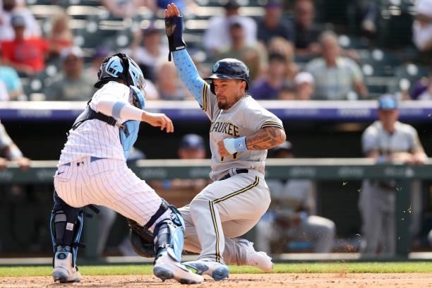 Jace Peterson of the Milwaukee Brewers scores past catcher Dom Nunez of the Colorado Rockies on a hit by Daniel Vogelbach in the ninth inning at...