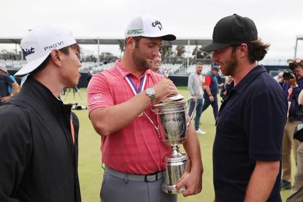 Jon Rahm of Spain is holds the trophy as he is congratulated by friends Kitaek Lee and Alberto Sanchez after winning during the final round of the...