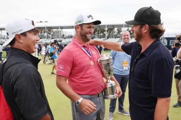 Jon Rahm of Spain is holds the trophy as he is congratulated by friends Kitaek Lee and Alberto Sanchez after winning during the final round of the...