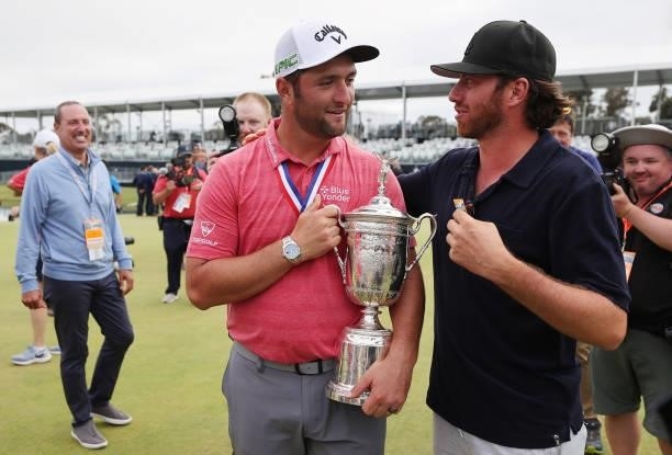 Jon Rahm of Spain is holds the trophy as he is congratulated by friend Alberto Sanchez after winning during the final round of the 2021 U.S. Open at...