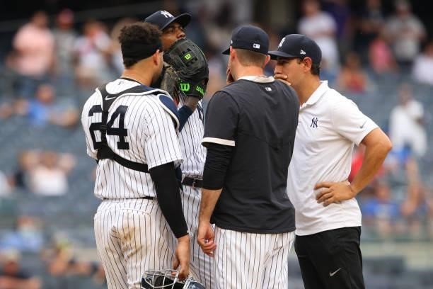 Pitcher Aroldis Chapman of the New York Yankees talks with catcher Gary Sanchez, pitching coach Matt Blake and trainer Tim Lentych during the ninth...