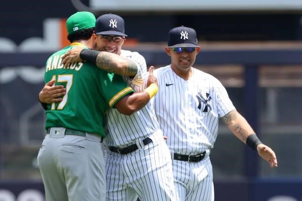 Elvis Andrus of the Oakland Athletics hugs Gleyber Torres of the New York Yankees as Rougned Odor of the Yankees looks on before a gameat Yankee...