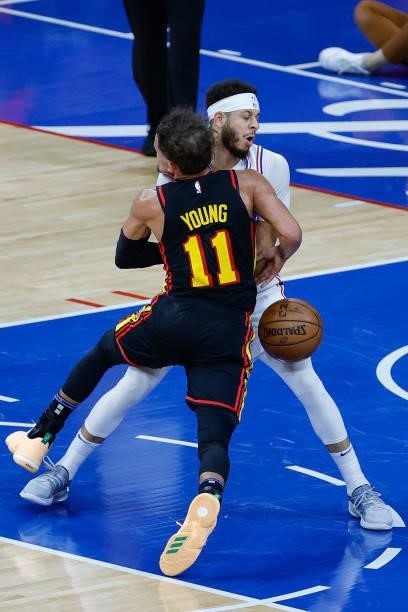 Trae Young of the Atlanta Hawks fouls Seth Curry of the Philadelphia 76ers during the second quarter during Game Seven of the Eastern Conference...