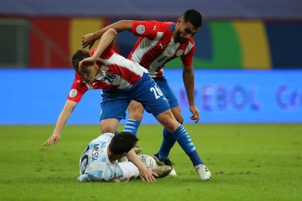 Lionel Messi of Argentina competes for the ball with Robert Piris da Motta and Junior Alonso of Paraguay during a group A match between Argentina and...