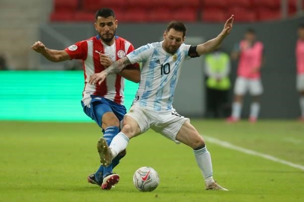 Junior Alonso of Paraguay competes for the ball with Lionel Messi of Argentina during a group A match between Argentina and Paraguay as part of...