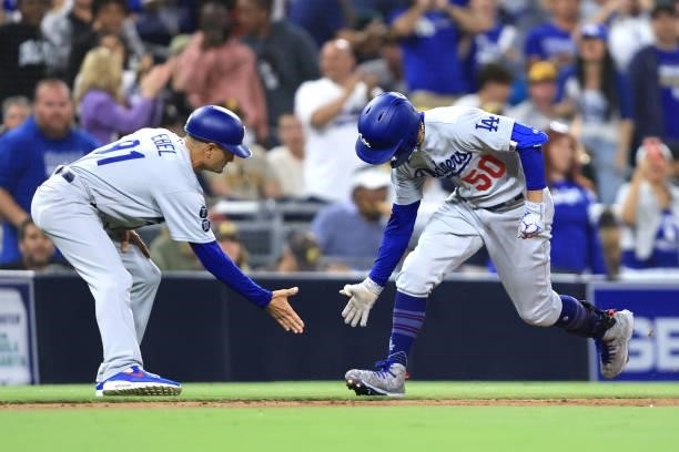Third base coach Dino Ebel congratulates Mookie Betts of the Los Angeles Dodgers as he rounds third base after hitting a solo homerun during the...