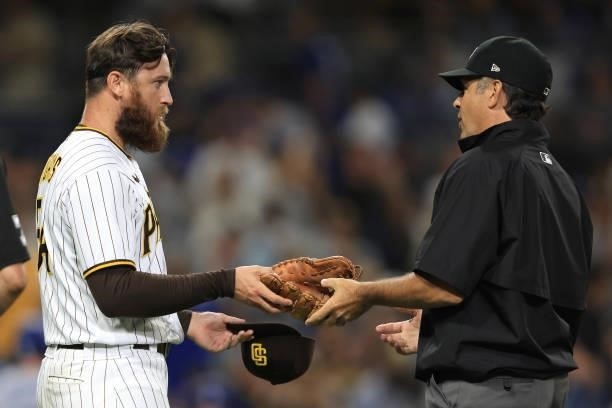 Austin Adams of the San Diego Padres has his glove inspected for foreign substances by umpire James Hoye during the seventh inning of a game at PETCO...