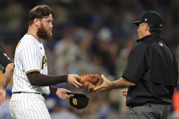 Austin Adams of the San Diego Padres has his glove inspected for foreign substances by umpire James Hoye during the seventh inning of a game at PETCO...