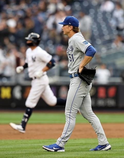 Brady Singer of the Kansas City Royals reacts as Kyle Higashioka of the New York Yankees rounds first base after a solo home run in the second inning...