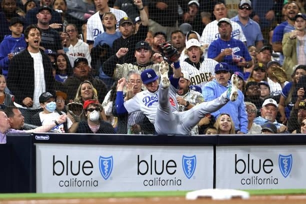 Gavin Lux of the Los Angeles Dodgers falls into the protective fence catching a foul ball hit by Jake Cronenworth of the San Diego Padres during the...