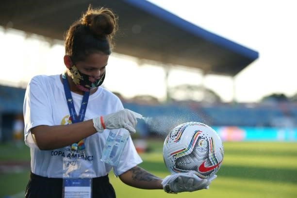 Copa America staff member disinfects a match ball prior to a Group B match between Ecuador and Peru as part of Copa America Brazil 2021 at Estadio...