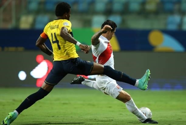 Gianluca Lapadula of Peru kicks the ball against Robert Arboleda of Ecuador to score the the first goal of his team during a Group B match between...