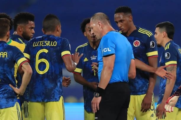 William Tesillo, Juan Cuadrado and Yerry Mina of Colombia argue with referee Nestor Pitana as he waits for VAR review of Brazil's goal during a Group...