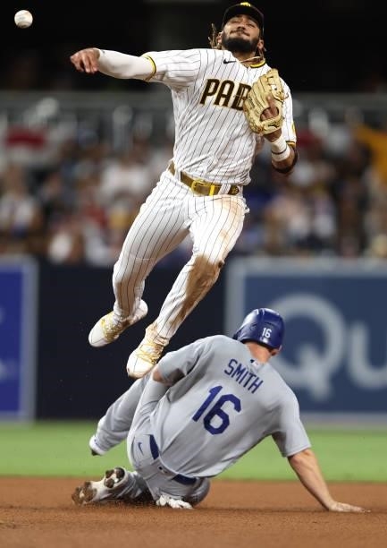 Fernando Tatis Jr. #23 of the San Diego Padres is unable to turn a double play as Will Smith slides into second base after a hit by Matt Beaty of the...