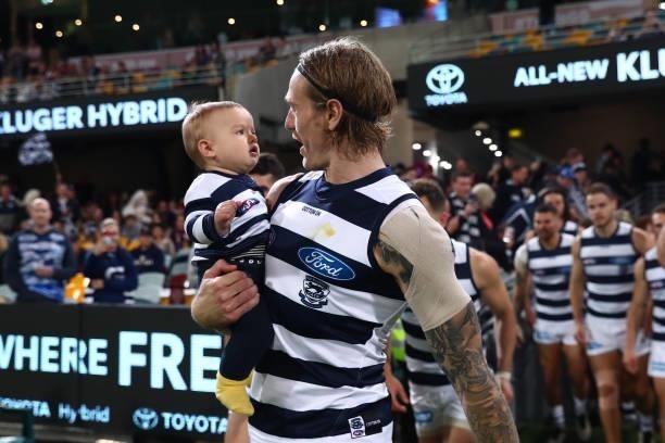 Tom Stewart of the Cats runs out for his 100th game with son Arthur during the round 14 AFL match between the Brisbane Lions and the Geelong Cats at...