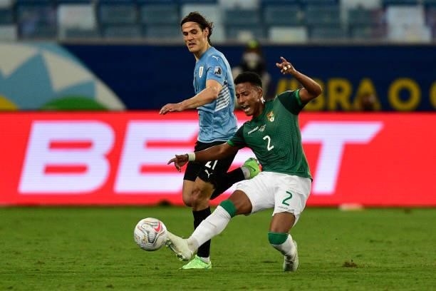 Jairo Quinteros of Bolivia kicks the ball against Edinson Cavani of Uruguay during a Group A match between Bolivia and Uruguay as part of Copa...