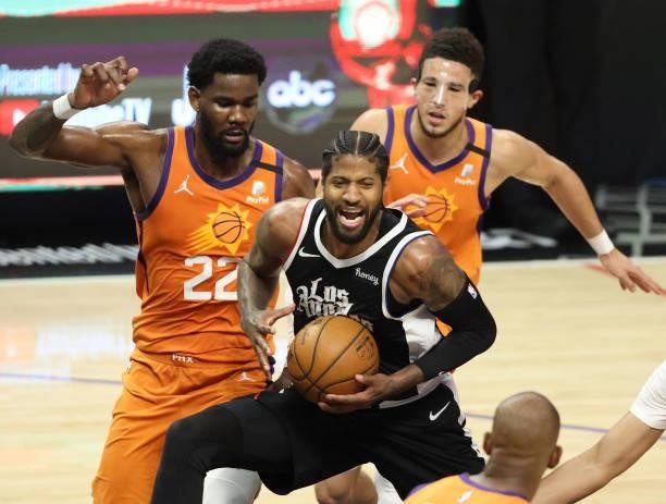 Paul George of the LA Clippers drives between Deandre Ayton and Devin Booker of the Phoenix Suns during the second half of game three of the Western...