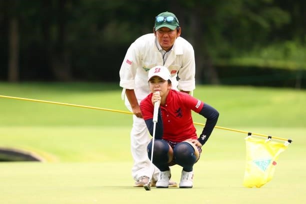 Kotone Hori of Japan lines up a putt with her coach and caddie Morihiro Mori on the 9th green during the second round of the Earth Mondamin Cup at...