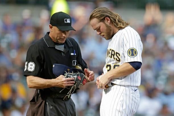 Corbin Burnes of the Milwaukee Brewers is searched for foreign substances by umpire Dan Iassogna in the fifth inning against the Colorado Rockies at...