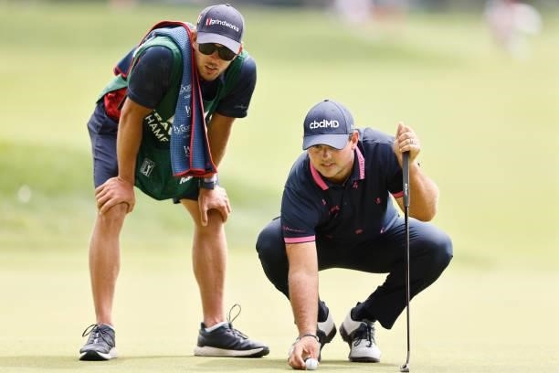 Patrick Reed of the United States talks with his caddie Kessler Karain on the seventh green during the second round of the Travelers Championship at...