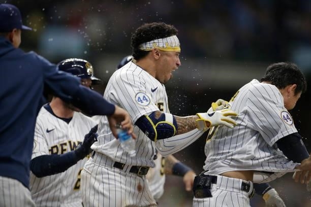 Kolten Wong of the Milwaukee Brewers chases Keston Hiura celebrating the walk off sacrifice fly in the eleventh inning against the Colorado Rockies...