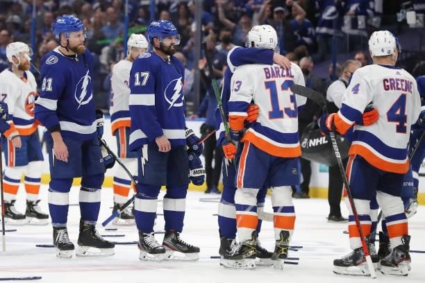 Andy Greene and Mathew Barzal of the New York Islanders shake hands with Alex Killorn and Erik Cernak of the Tampa Bay Lightning after the...