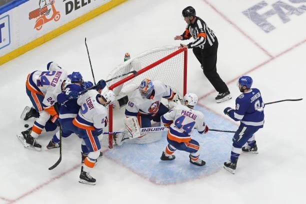 Scott Mayfield of the New York Islanders attempts to control the puck against Pat Maroon and Ross Colton of the Tampa Bay Lightning as Semyon...