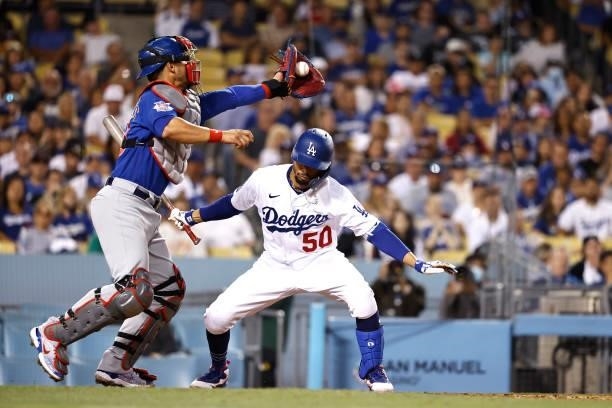 Willson Contreras of the Chicago Cubs reaches for a ball over Mookie Betts of the Los Angeles Dodgers after losing control of it during the sixth...
