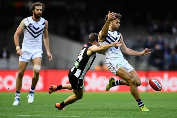 Griffin Logue of the Dockers kicks as he is tackled by Josh Thomas of the Magpies during the round 15 AFL match between the Collingwood Magpies and...