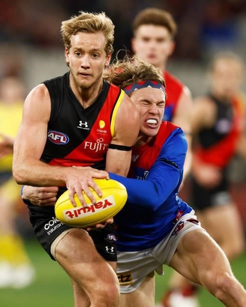 Darcy Parish of the Bombers is tackled by Jayden Hunt of the Demons during the round 15 AFL match between the Essendon Bombers and the Melbourne...