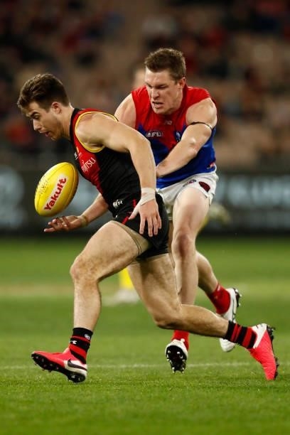 Tom McDonald of the Demons chases Zach Merrett of the Bombers during the round 15 AFL match between the Essendon Bombers and the Melbourne Demons at...