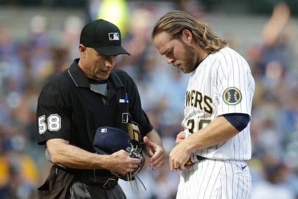 Corbin Burnes of the Milwaukee Brewers is checked by umpire Dan Iassogna for any foreign substance against the Colorado Rockies at American Family...