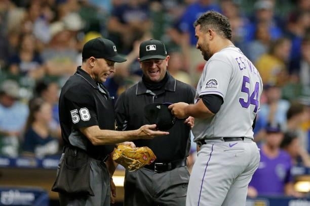 Carlos Estevez of the Colorado Rockies shares a laugh with umpire Dan Iassogna while being checked for a foreign substance against the Milwaukee...