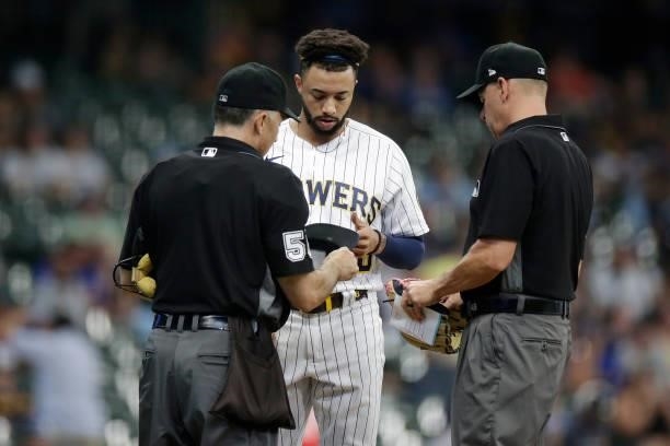Devin Williams of the Milwaukee Brewers is checked by umpire Dan Iassogna for any foreign substance against the Colorado Rockies at American Family...