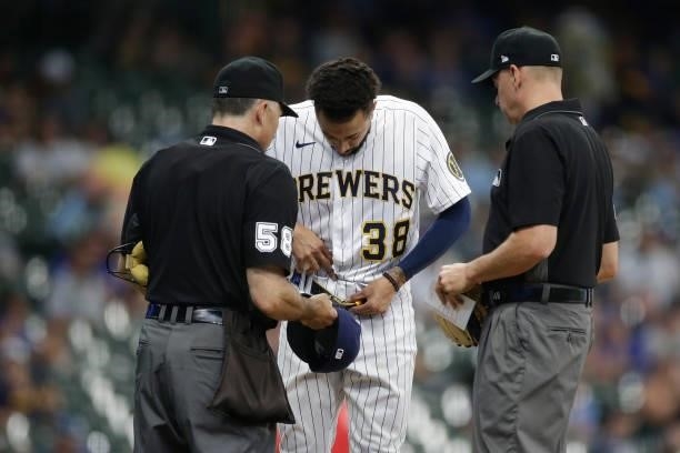 Devin Williams of the Milwaukee Brewers is checked by umpire Dan Iassogna for any foreign substance against the Colorado Rockies at American Family...
