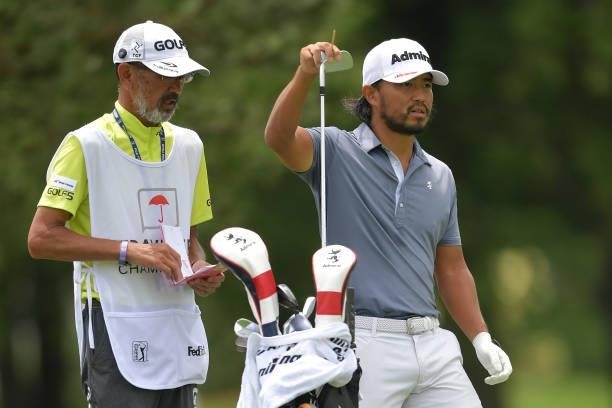 Satoshi Kodaira of Japan talks with his caddie on the fifth hole during the third round of the Travelers Championship at TPC River Highlands on June...